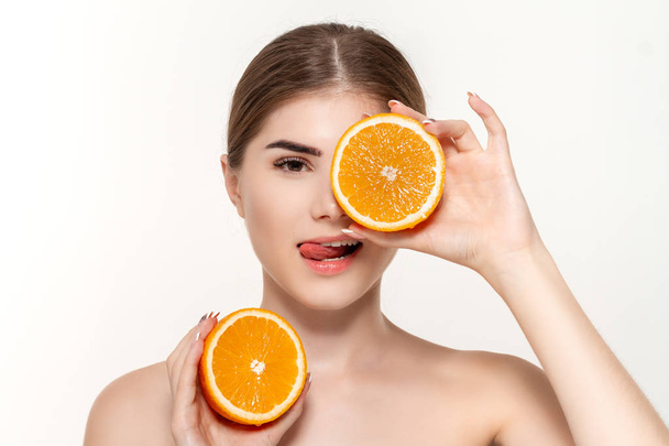 Close-up portrait of a happy beautiful young girl holding half of oranges close to face isolated over white background. - Photo, Image