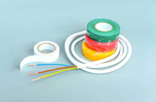 Set of multicolored insulating tapes and white cable on gray bac - Photo, Image