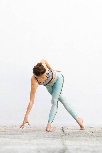 Vestibilità sportiva ragazza attiva nella moda abbigliamento sportivo fare esercizio di fitness yoga di fronte al muro grigio, sport all'aria aperta, stile urbano
 - Foto, immagini