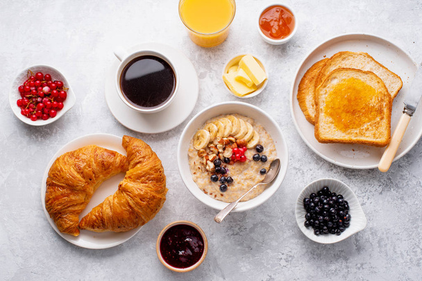 Breakfast with oatmeal and berries with croissants and toasts on table  - Foto, Imagem