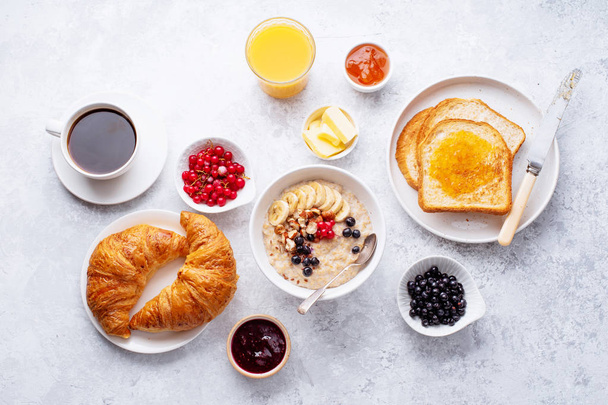 Breakfast with oatmeal and berries with croissants and toasts on table  - Φωτογραφία, εικόνα