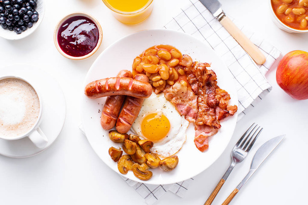 fried bacon with mushrooms and egg on plate served with orange juice and coffee on white table, classical english breakfast concept  - Foto, immagini