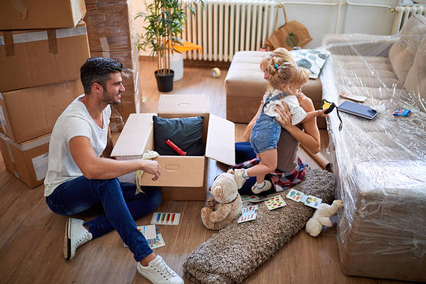 parents and daughter, unpacking boxes and moving into a new home - Valokuva, kuva