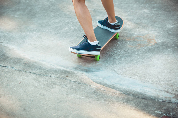 Skateboarder legs skateboarding at skatepark in city - Fotó, kép
