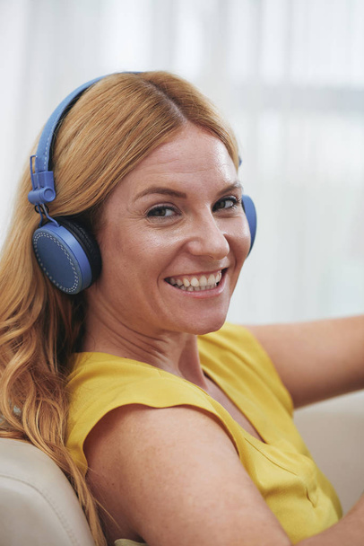Портрет счастливой молодой женщины в наушниках, слушающей музыку, подкаст или аудиокнигу
 - Фото, изображение
