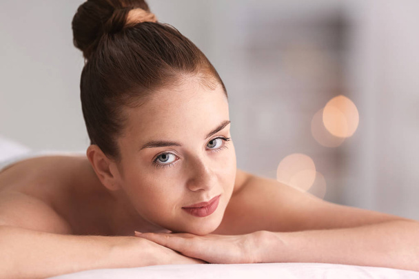 Beautiful young woman relaxing in spa salon - Фото, изображение