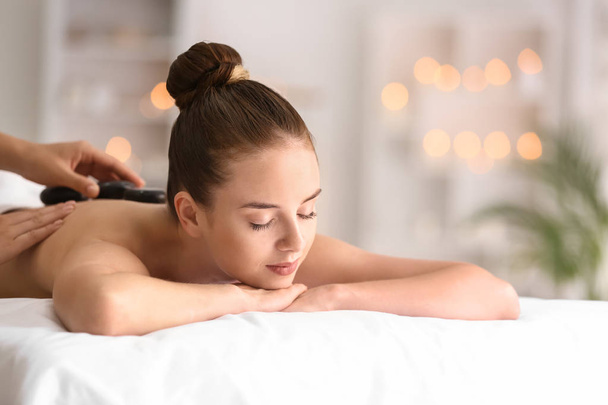 Jeune femme subissant une thérapie aux pierres chaudes dans un salon de spa
 - Photo, image