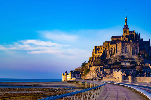 Magnifique château médiéval du Mont Saint Michel, France. L'abbaye, située sur l'île, est clôturée de fortifications. Le pont mène à l'île. Beau ciel bleu et nuages blancs moelleux. Pendant la journée
 - Photo, image