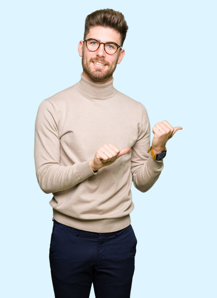 Νέοι επαγγελματίες όμορφος άνθρωπος φορώντας γυαλιά κατάδειξης στο πίσω πίσω από το χέρι με μπράβο, χαμογελώντας αυτοπεποίθηση - Φωτογραφία, εικόνα