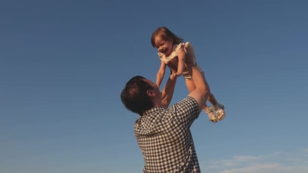 Isä oksentaa onnellisen tyttären siniselle taivaalle. Isä ja pieni lapsi leikkivät, nauravat ja halaavat yhdessä. Onnellinen perhe matkustaa. Vauva vanhemman sylissä. Isän vapaapäivä. Onnellisen perheen käsite. - Materiaali, video