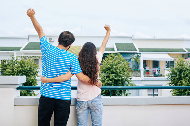 Szczęśliwy przytulanie para podnoszenie rąk i obchodzi zakup nowego domu, widok z tyłu - Zdjęcie, obraz