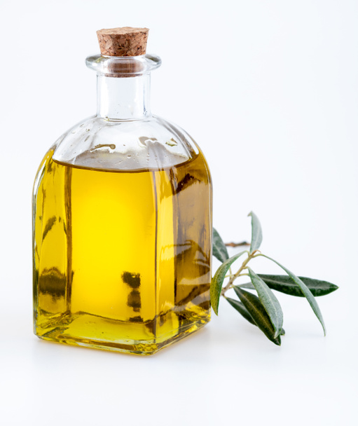 Extra szűz olívaolaj üvegpalackban. Előtér. Ide tartoznak a levelek és az olíva ágak. Elszigetelt fehér alapon. - Fotó, kép
