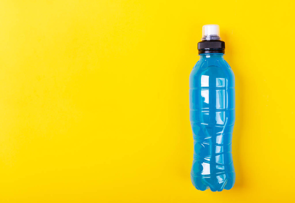 Isotonic energy drink. Bottles with blue transparent liquid, sport beverage on a yellow background - Fotó, kép
