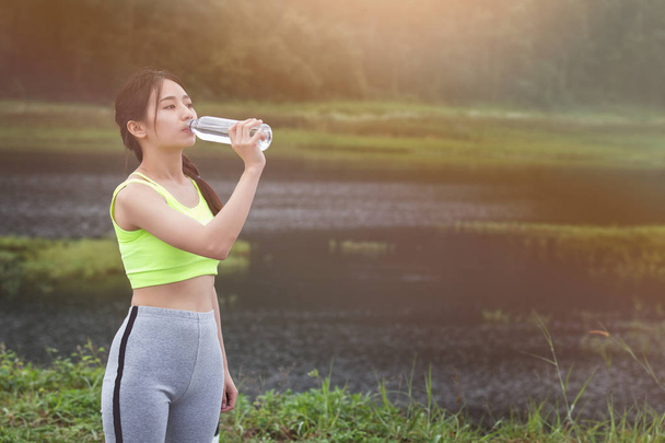 Menina fitness saudável atraente beber água após o treino. Runner menina ter um descanso após o treinamento
. - Foto, Imagem