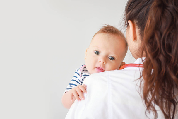 Pediatra con pequeño bebé sobre fondo claro
 - Foto, imagen