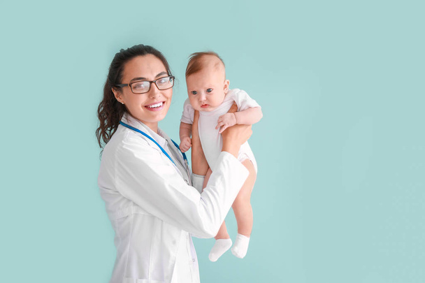 Pediatrician with cute little baby on color background - Foto, Imagen