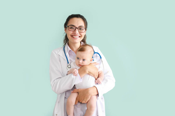 Παιδίατρος με χαριτωμένο μικρό μωρό σε χρώμα φόντου - Φωτογραφία, εικόνα