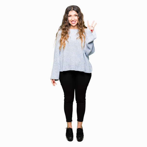 Young beautiful woman wearing winter sweater showing and pointing up with fingers number three while smiling confident and happy. - Valokuva, kuva