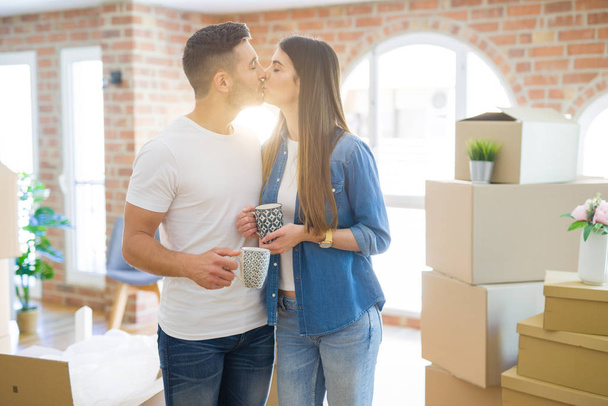 Hermosa pareja mudándose a una nueva casa, sonriendo alegre bebiendo una taza de café
 - Foto, Imagen