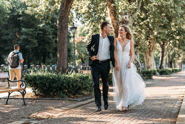 Bride and groom hugging in the old town street. Wedding couple in love. Luxury rhinestone dress. Hot summer days. - Photo, image