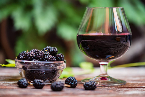 Zamknąć świeże owoce morwy w misce i wino w szklance - Zdjęcie, obraz
