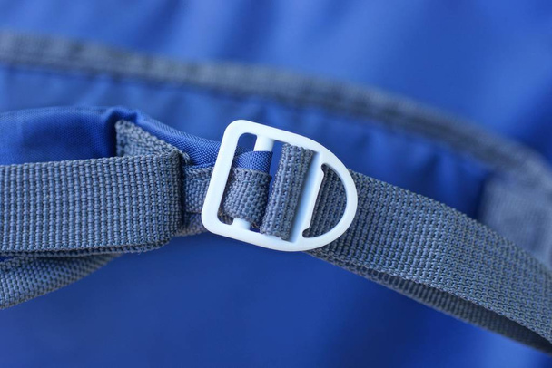 one white carabiner on a gray harness on a blue background - Photo, Image