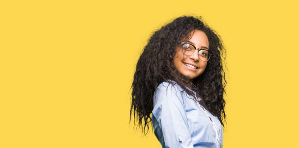 Young beautiful business girl with curly hair wearing glasses Inviting to enter smiling natural with open hand - Фото, зображення