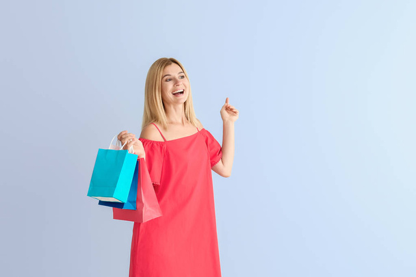 Happy beautiful woman with shopping bags on color background - Photo, Image