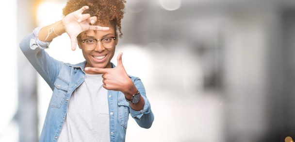 Όμορφη νεαρή αφρικανική αμερικανική γυναίκα που φοράει γυαλιά, πέρα από το απομονωμένο υπόβαθρο χαμογελώντας καρέ κάνοντας με τα χέρια και τα δάχτυλα με χαρούμενο πρόσωπο. Έννοια της δημιουργικότητας και της φωτογραφίας. - Φωτογραφία, εικόνα