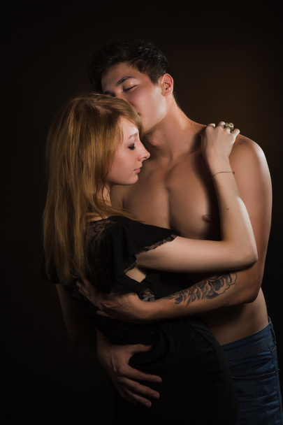 Beautiful young couple hugging and kissing isolated on black background. - Fotoğraf, Görsel