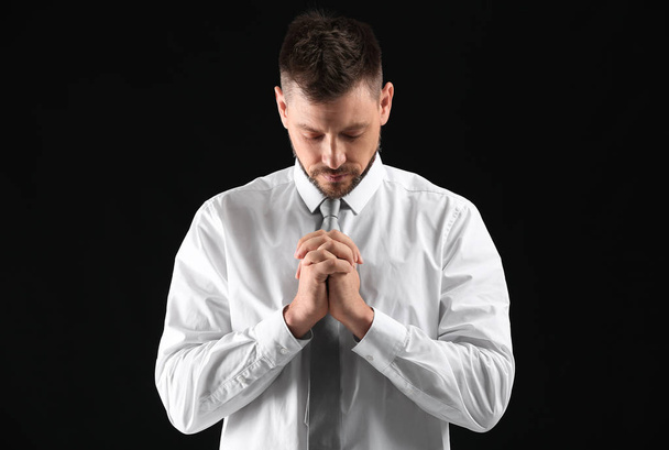 Religious man praying on dark background - Fotoğraf, Görsel