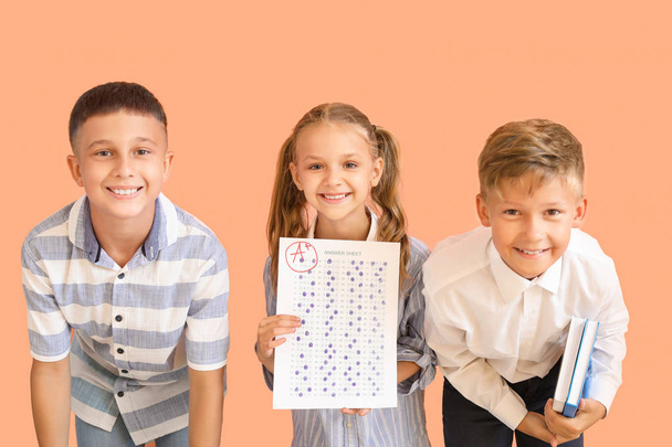 Enfants heureux avec feuille de réponse pour le test scolaire sur fond de couleur
 - Photo, image