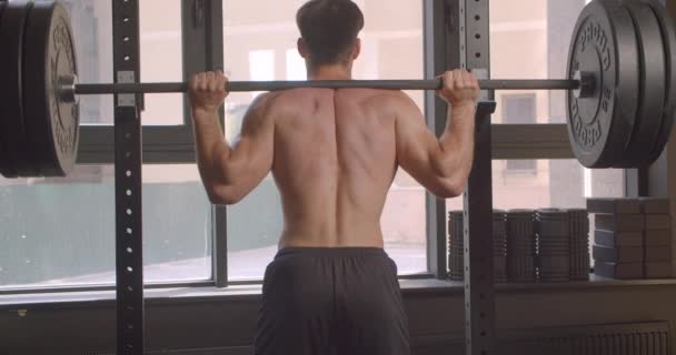 Closeup back view portrait of adult shirtless muscular caucasian man powerlifting in the gym indoors - Felvétel, videó