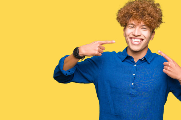 Young handsome elegant man with afro hair smiling confident showing and pointing with fingers teeth and mouth. Health concept. - Photo, Image