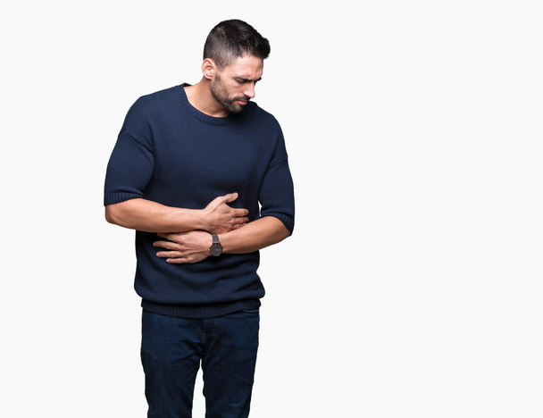 Young handsome man wearing sweater over isolated background with hand on stomach because nausea, painful disease feeling unwell. Ache concept. - Photo, Image