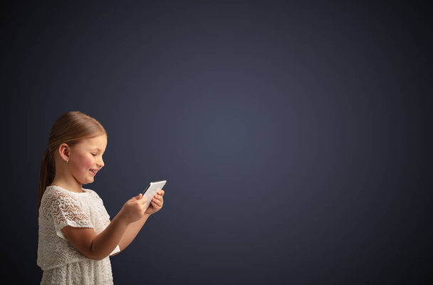 Cute little girl using tablet with dark background - Foto, immagini