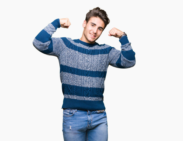 Joven hombre guapo sobre fondo aislado mostrando los músculos de los brazos sonriendo orgulloso. Concepto Fitness
. - Foto, imagen