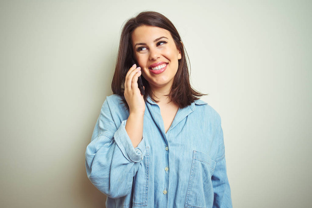 Young beautiful woman having a conversation using smartphone over isolated background with a happy face standing and smiling with a confident smile showing teeth - Φωτογραφία, εικόνα