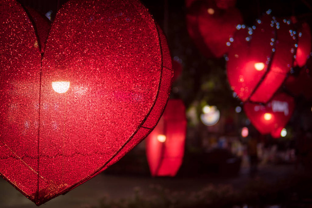 Piros szív alakú lámpa sötét éjszakában. Fénykép lámpa formájú szív az étteremben. - Fotó, kép