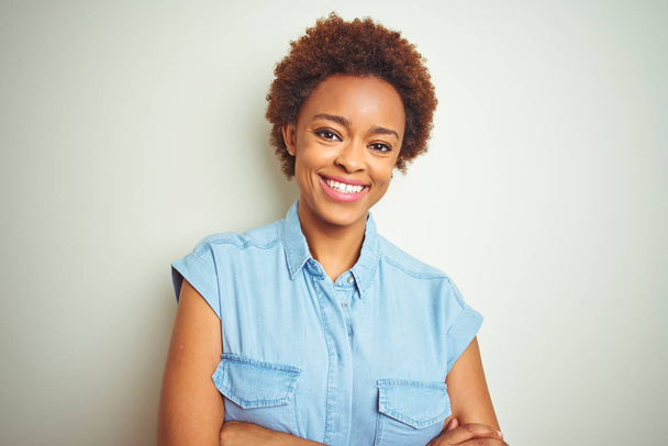 Młoda piękna Afrykańska amerykańska kobieta z włosami Afro na białym tle szczęśliwy twarzy uśmiechnięty z skrzyżowanymi ramionami patrząc na kamerę. Osoba pozytywna. - Zdjęcie, obraz