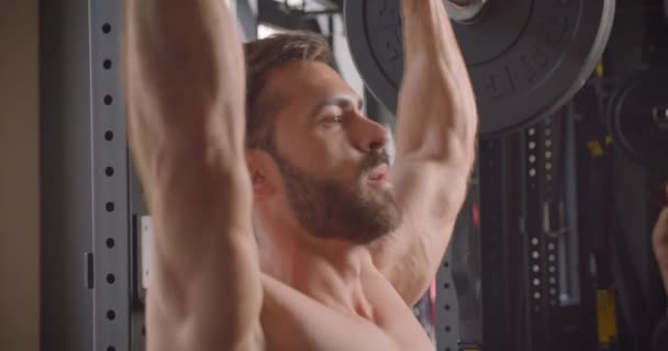 Closeup side view portrait of handsome shirtless muscular caucasian man powerlifting in the gym indoors - Metraje, vídeo