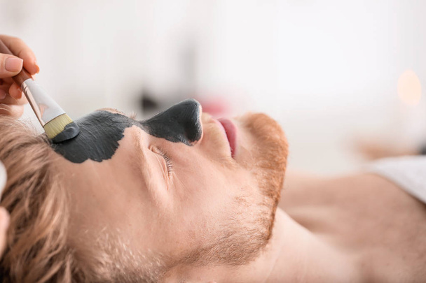 Kosmetolog nakładający maskę na twarz człowieka w salonie spa - Zdjęcie, obraz