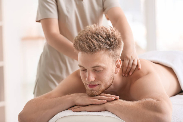 Handsome young man receiving massage in spa salon - Photo, Image