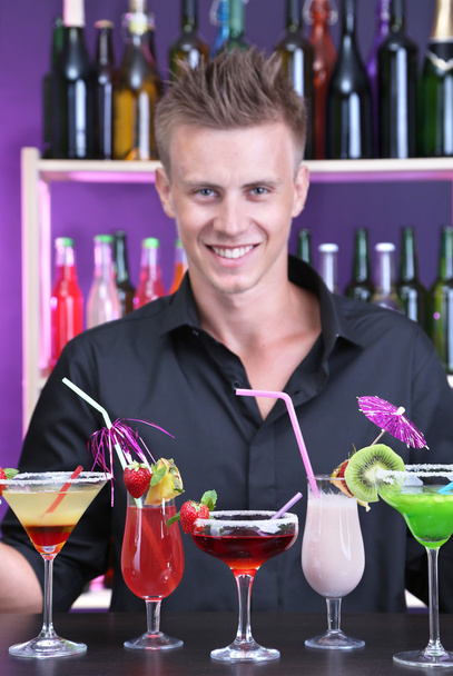 Portrait of handsome barman with different cocktails cocktail, at bar - Photo, image