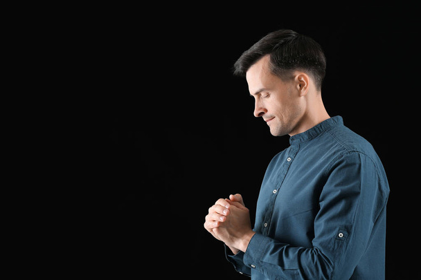 Religious man praying to God on dark background - Photo, Image