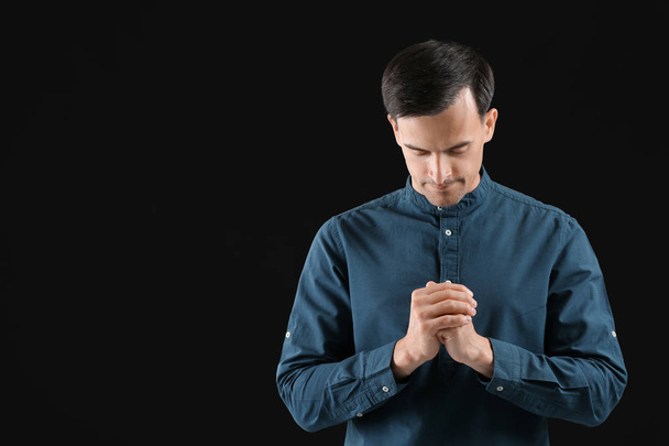 Religious man praying to God on dark background - Foto, Bild