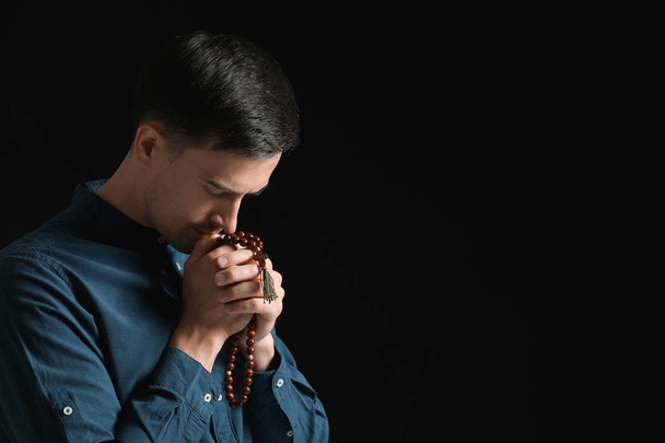 Religious man praying to God on dark background - Valokuva, kuva