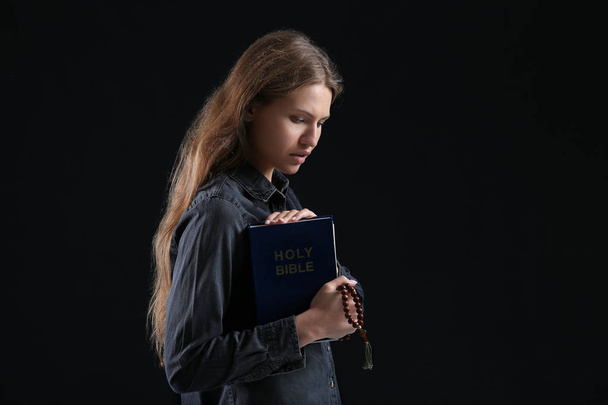 Jeune femme religieuse priant Dieu sur fond sombre - Photo, image