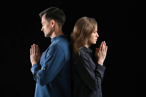 Religiöses Paar betet zu Gott auf dunklem Hintergrund - Foto, Bild