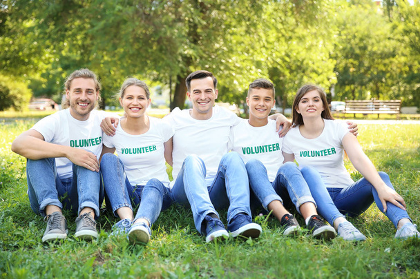 Grupo de voluntarios sentados en césped verde al aire libre
 - Foto, Imagen